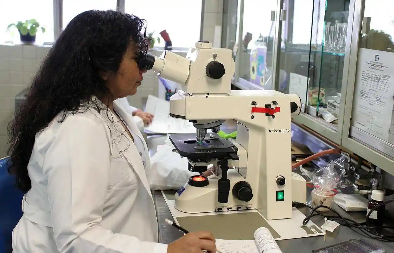 Scientist handling lab glassware under bright ambient light.